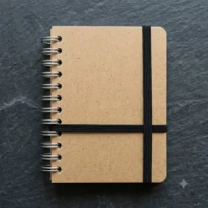 A closed pocket-sized spiral bound journal secured with a black elastic band.